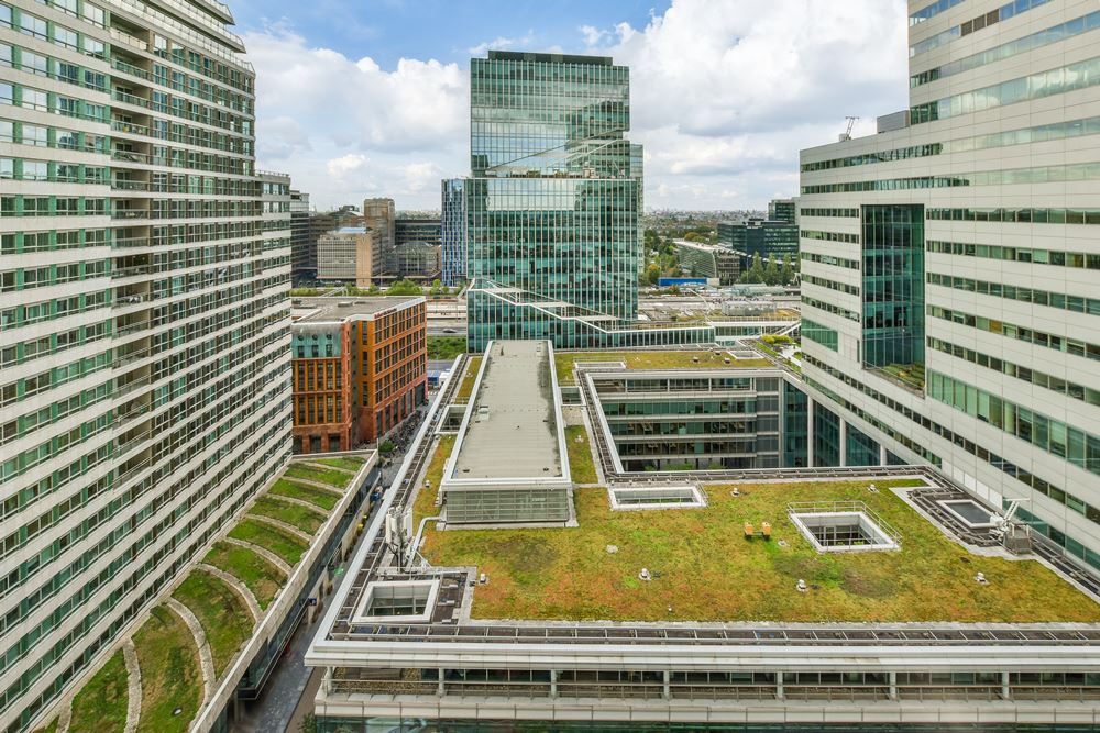 a roof top view of a city with buildings and green roofing