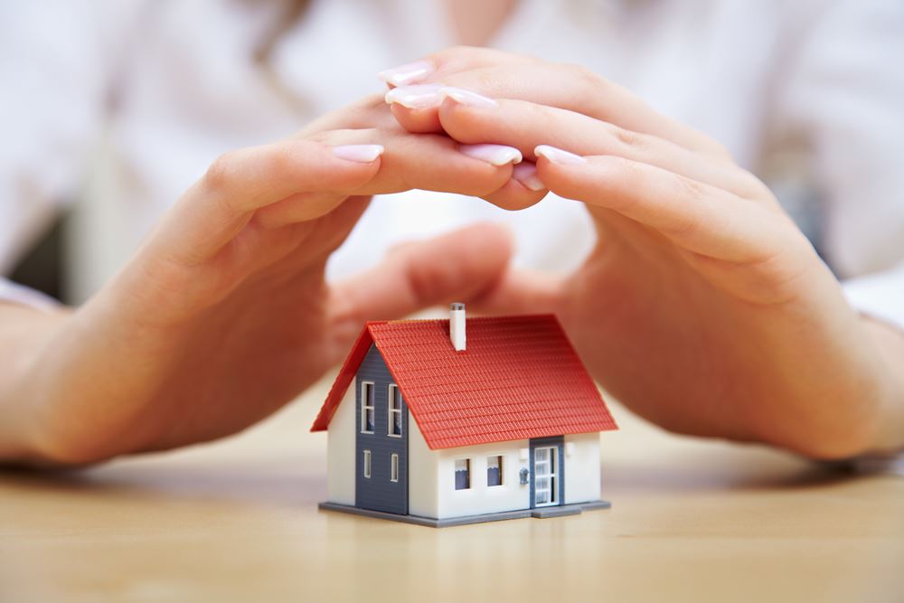 Small house with hands over it as a concept for what to do if insurance denied roof claim